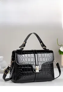 Detail of black faux crocodile skin handbag with golden metal twist lock and handle