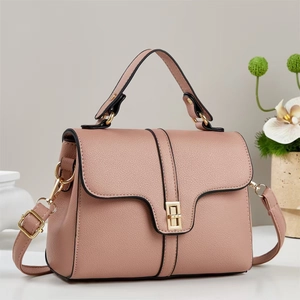 Detail of dusty rose pebbled leather handbag with gold square lock and black edge finish