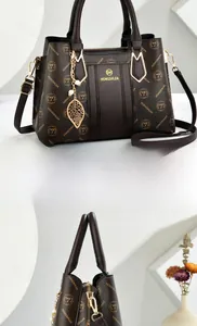 Detail of dark brown monogram tote bag with gold hardware and side leaf pendant