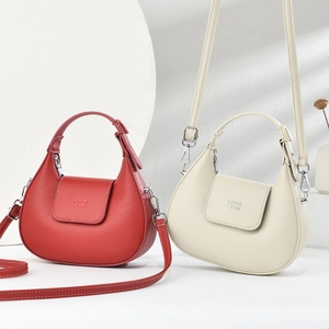 Detail view of crescent hobo bags in red and beige showing fine pebbled leather texture