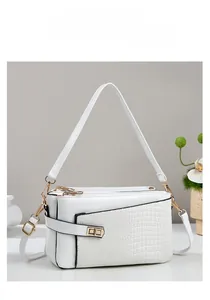 Detail of white square handbag showing crocodile embossed texture and gold metal clasp