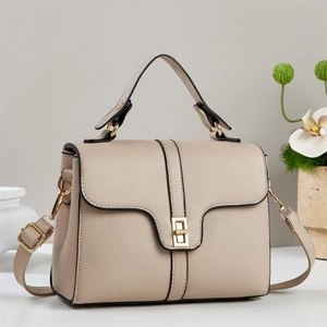 Elegant beige square handbag with gold buckle and top handle shown in a minimalist setting