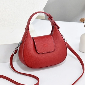Close-up of red crescent bag with lychee texture leather and silver metal hardware