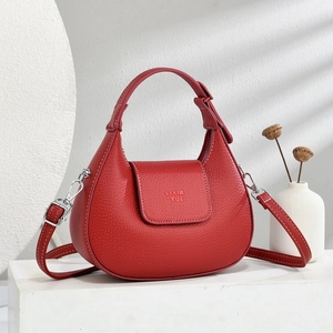 Detail of red crescent hobo bag in lychee pattern leather with embossed logo on the flap