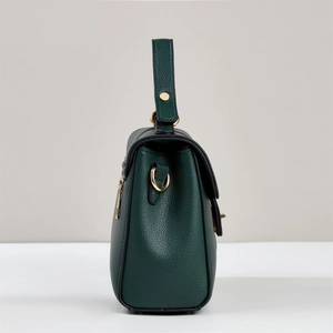 Detail view of dark green lychee textured leather bag with gold-tone hardware and stitching