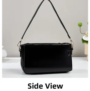 Side view of black glossy patent leather handbag with gold metal hardware and adjustable strap