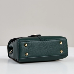 Macro detail of dark green lychee leather handbag bottom with four gold metal feet