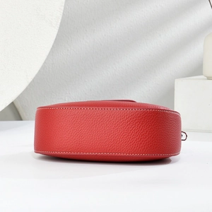 Close-up of red pebbled leather moon bag with contrast white stitching and silver hardware