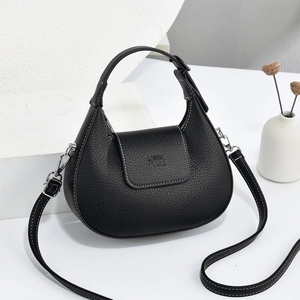 Detail of black crescent crossbody bag showing litchi grain texture and silver hardware