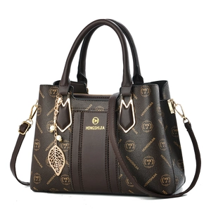 Brown monogram handbag with golden leaf charm and adjustable shoulder strap