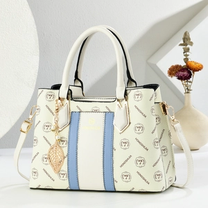 Elegant cream tote bag with blue trim and gold hardware in a minimalist studio setting