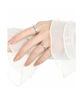 Bagues minimalistes en argent mat portées aux doigts sur fond de tissu blanc doux