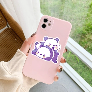 Pink silicone phone case with a purple cartoon panda pattern held against a soft lawn backdrop