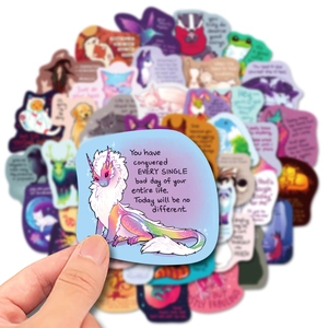 Detail shot of a hand holding a colorful hand-drawn dragon sticker with inspirational quote