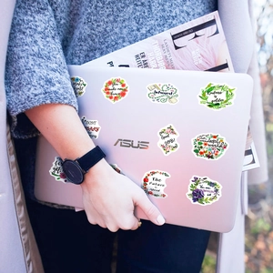 Détail d'autocollants floraux motivants sur un ordinateur avec un magazine de mode en fond