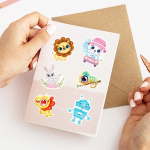 Hands holding a greeting card decorated with colorful cute animal and robot stickers
