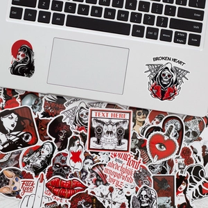 Detail of gothic punk stickers on a silver laptop featuring skulls and red devil motifs