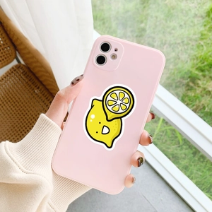 Pink silicone phone case with cartoon lemon pattern held in hand against garden background