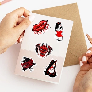 Detailed view of red and black gothic stickers featuring horror devil designs and band art