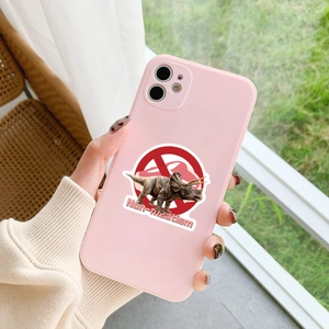 Pink phone case with a triceratops sticker and non-meatism text held in a hand outdoors