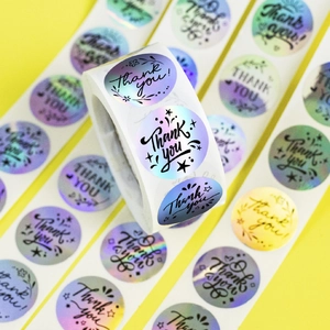 Detail view of 1 inch holographic rainbow Thank You roll stickers with artistic font