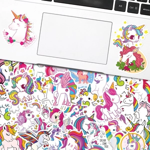 Nahaufnahme bunter Einhorn-Aufkleber auf einem Laptop und verstreute dekorative Muster