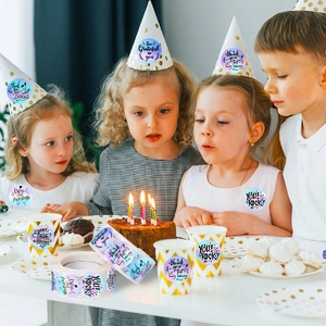 Children at a birthday party using holographic laser thank you stickers on party hats and cups