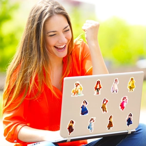 Girl character stickers on a laptop surface shown in natural outdoor sunlight