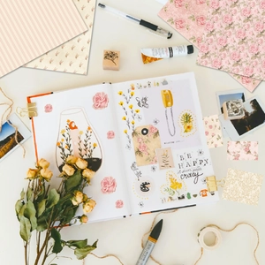 Detailed flat lay of vintage floral scrapbook papers with pink roses and DIY craft tools