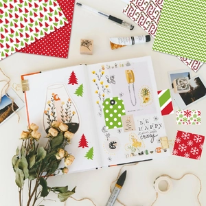 Flat lay of Christmas DIY scrapbooking paper with festive patterns and stickers