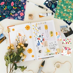Artistic layout of floral scrapbooking paper with labels and stationery on desk