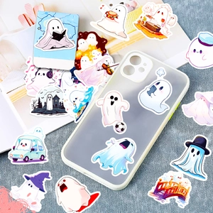 Various cute cartoon ghost stickers applied on a phone case and scattered on a desk