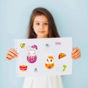 Detailed view of child holding DIY Easter cartoon stickers with bunnies and eggs
