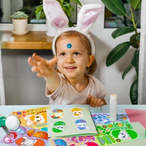 Girl creating DIY Easter crafts with cartoon bunny stickers and colorful eggs
