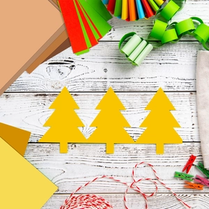 Dettaglio di ritagli di carta a forma di albero di Natale giallo su un banco da lavoro