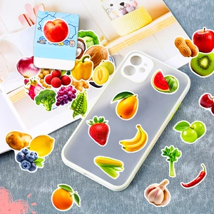 Detailansicht bunter Obst- und Gemüsesticker auf einer Handyhülle und Magazinhintergrund