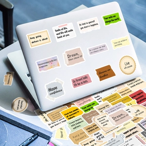 Close-up of motivational English quote stickers on a laptop surface for decoration