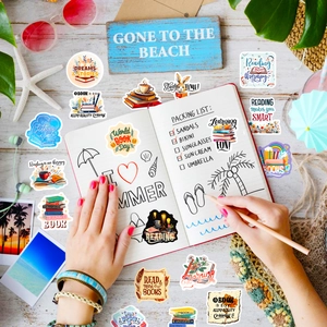 Flat lay of reading and summer vinyl stickers on a wooden desk with travel props