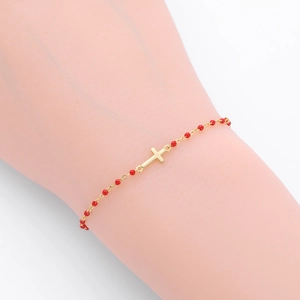 Détail du bracelet en argent S925 doré avec perles rouges et un pendentif croix