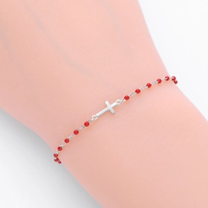 Détail du bracelet croix en argent sterling S925 avec perles rouges sur un présentoir