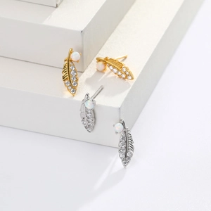 Close-up of feather earrings with white opal and cubic zirconia in gold and silver
