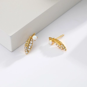 Detailed view of gold feather stud earrings inlaid with cubic zirconia and opal