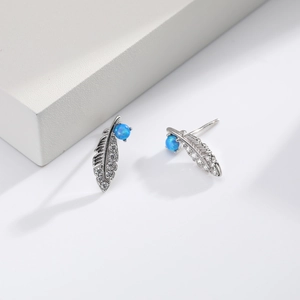 Macro detail of silver feather stud earrings with sparkling cubic zirconia and blue opal