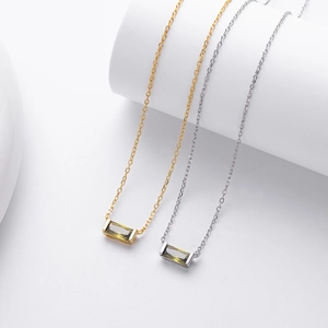Detail of silver and gold necklaces featuring emerald-cut green cubic zirconia stones