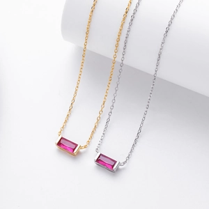 Close-up of S925 silver necklaces with baguette-cut red gemstones and polished finish