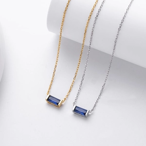 Close-up of minimalist rectangular dark blue sapphire pendant in gold and silver finish