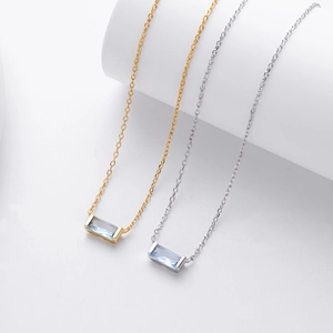 Detailed shot of two square cut light blue zircon necklaces in gold and silver plating