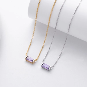 Detail of silver and gold necklaces featuring rectangular purple zircon stones on display