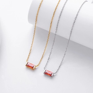 Close-up of elegant gold and silver necklaces with rectangular red zircon pendants