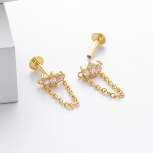 Détail de boucles d'oreilles couronne dorées avec trois zircons marquises et chaîne